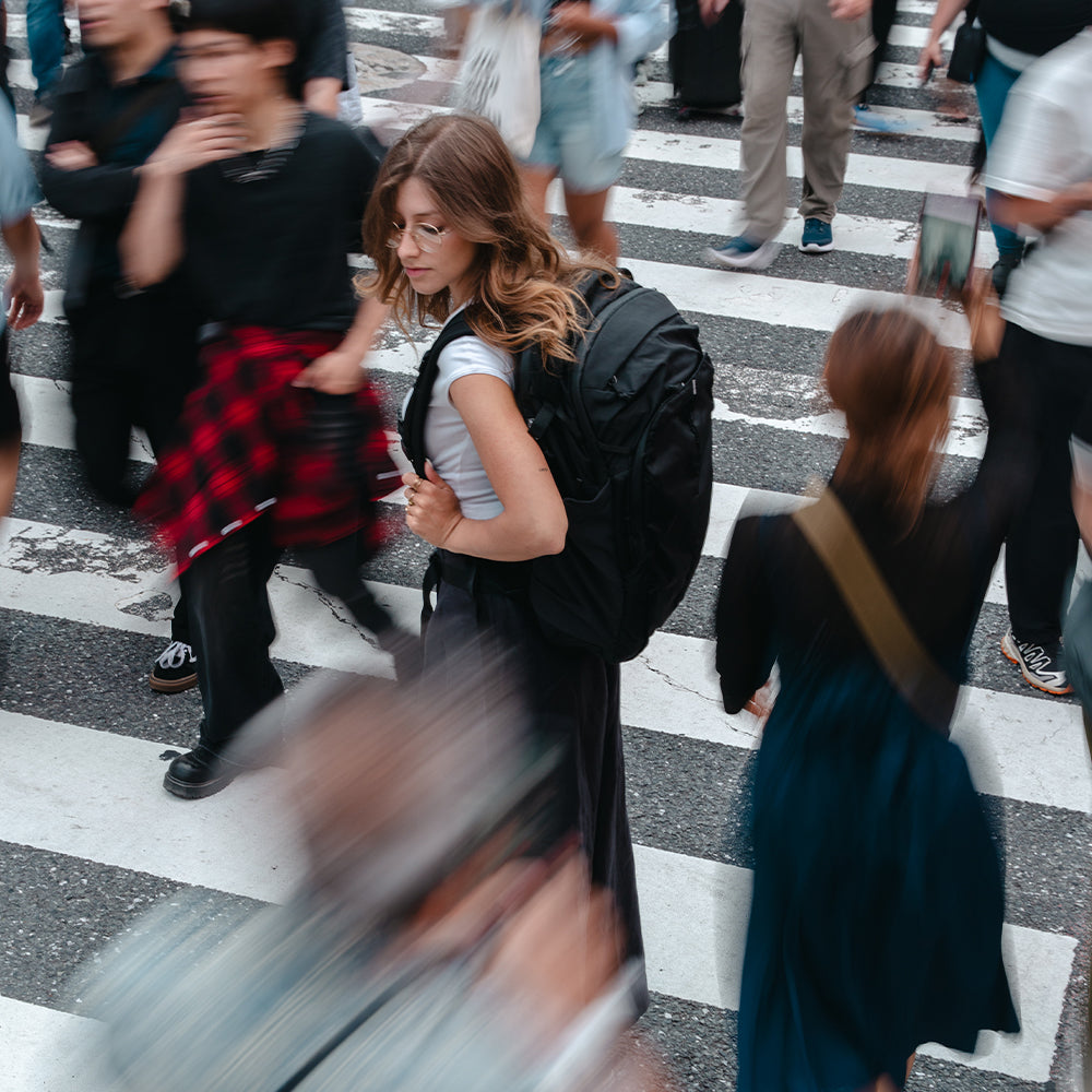 person walking in busy crosswalk with black backpack