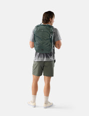 Person wearing a green backpack and shorts on a white background