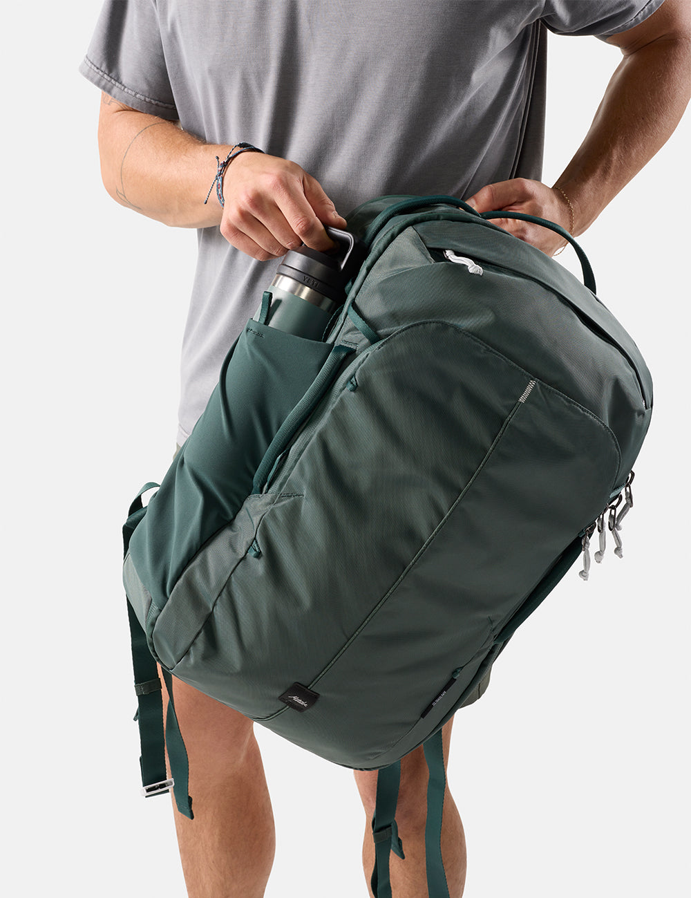pulling water bottle out of green backpack