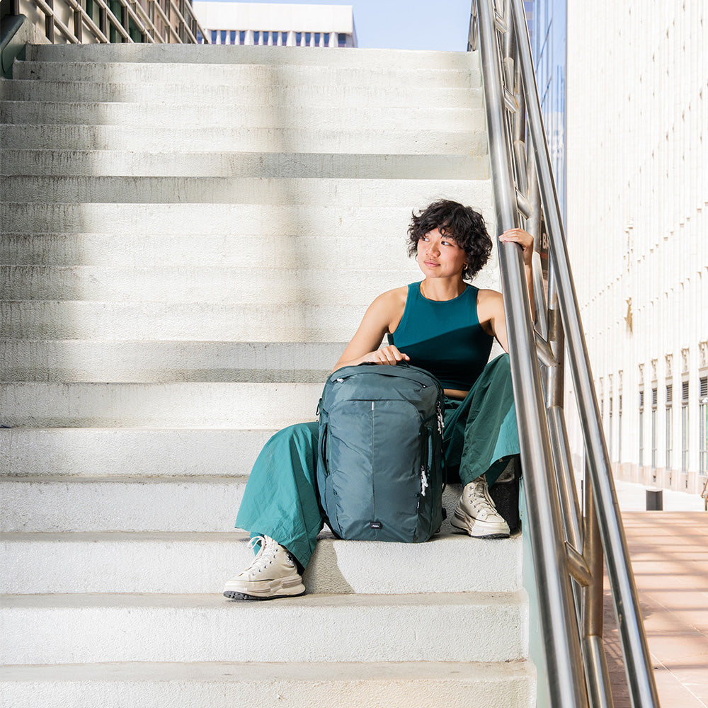 person sitting on concrete stairs with juniper backpack