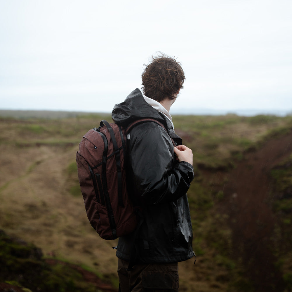 person in moody landscape wearing garnet backpack