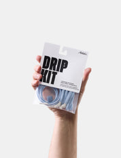 Hand holding a 'Drip Kit' packaging with a white background