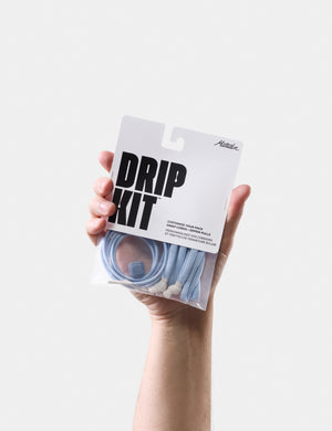 Hand holding a 'Drip Kit' packaging with a white background