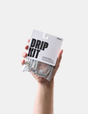 Hand holding a 'Drip Kit' packaging against a white background