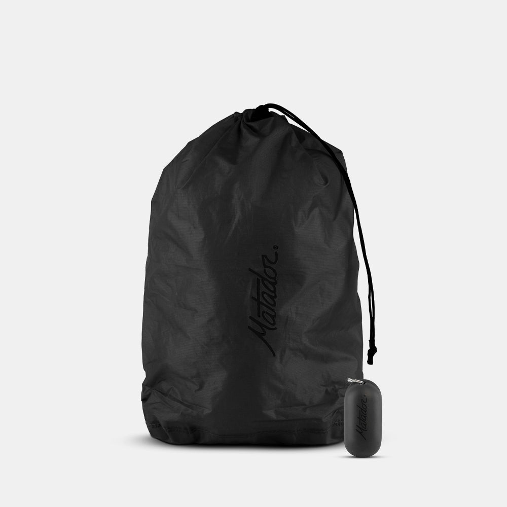 Black drawstring bag with a small black container on a light gray background