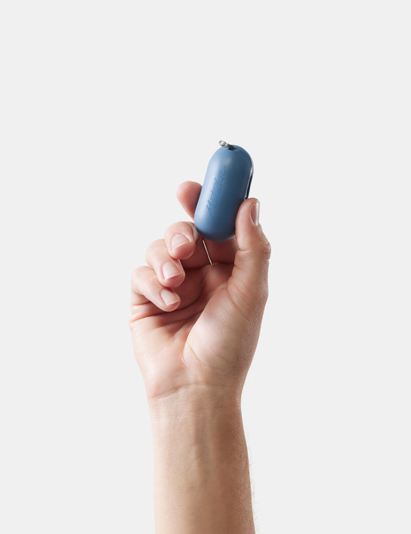 Hand holding a small blue object against a white background