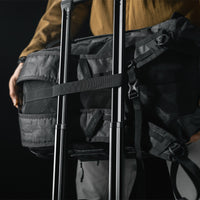 black backpack being placed on rolling luggage handle