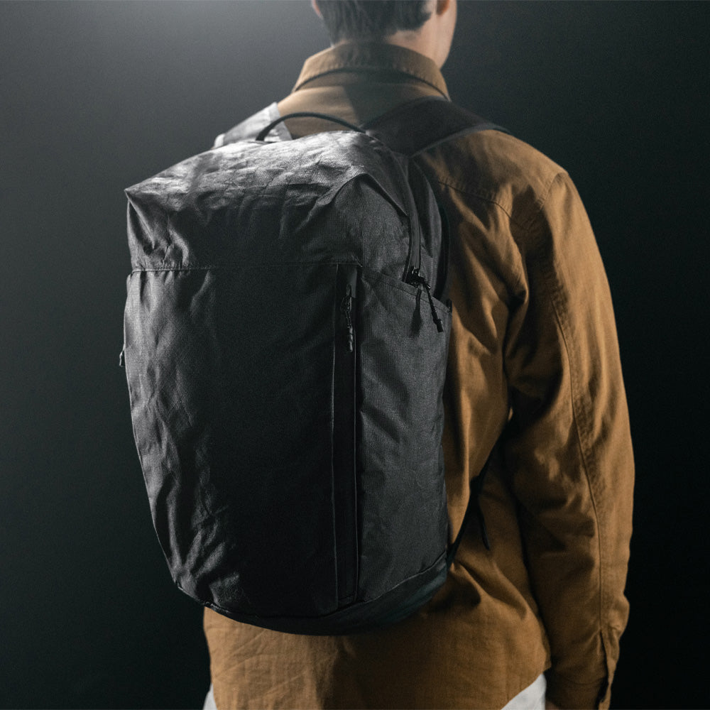 man on black studio background wearing black backpack