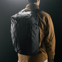 man on black studio background wearing black backpack
