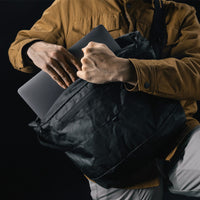 man pulling laptop out of black messenger bag