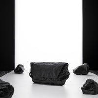 black sling bag on light up white studio background