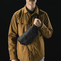 man on black studio background wearing black sling across his front