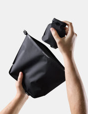 Person holding a Black toiletry case with a soap bar case on a light gray background