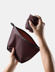 Person holding a Garnet toiletry bag and soap bar case against a white background