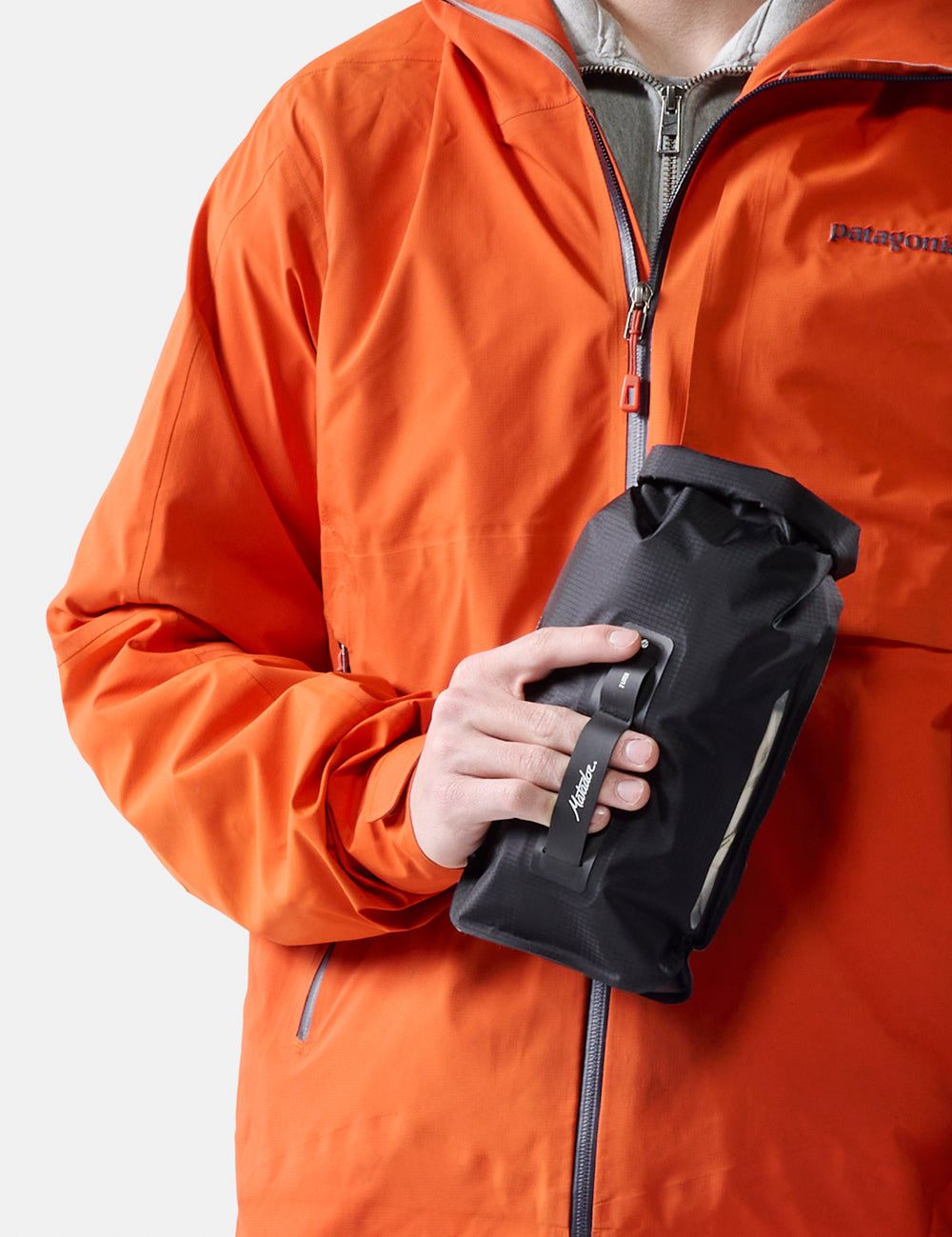 Person wearing an orange raincoat holding a black bag on a white background