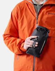 Person wearing an orange raincoat holding a black bag on a white background