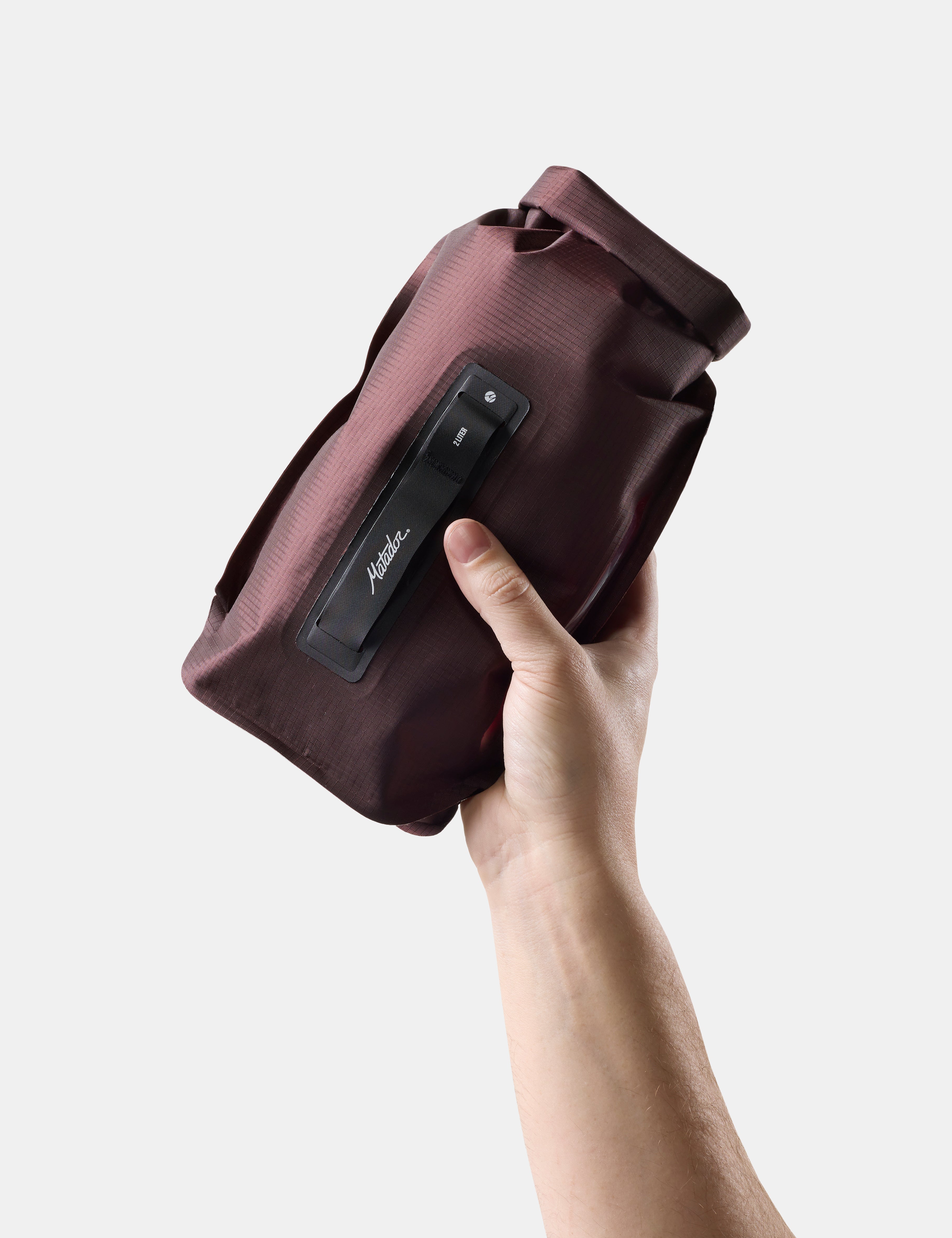 hand holding garnet dry bag on white background