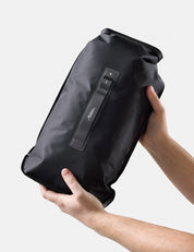 Black dry bag held by a person against a light gray background