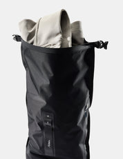 Black dry bag containing a light-colored jacket on a white background