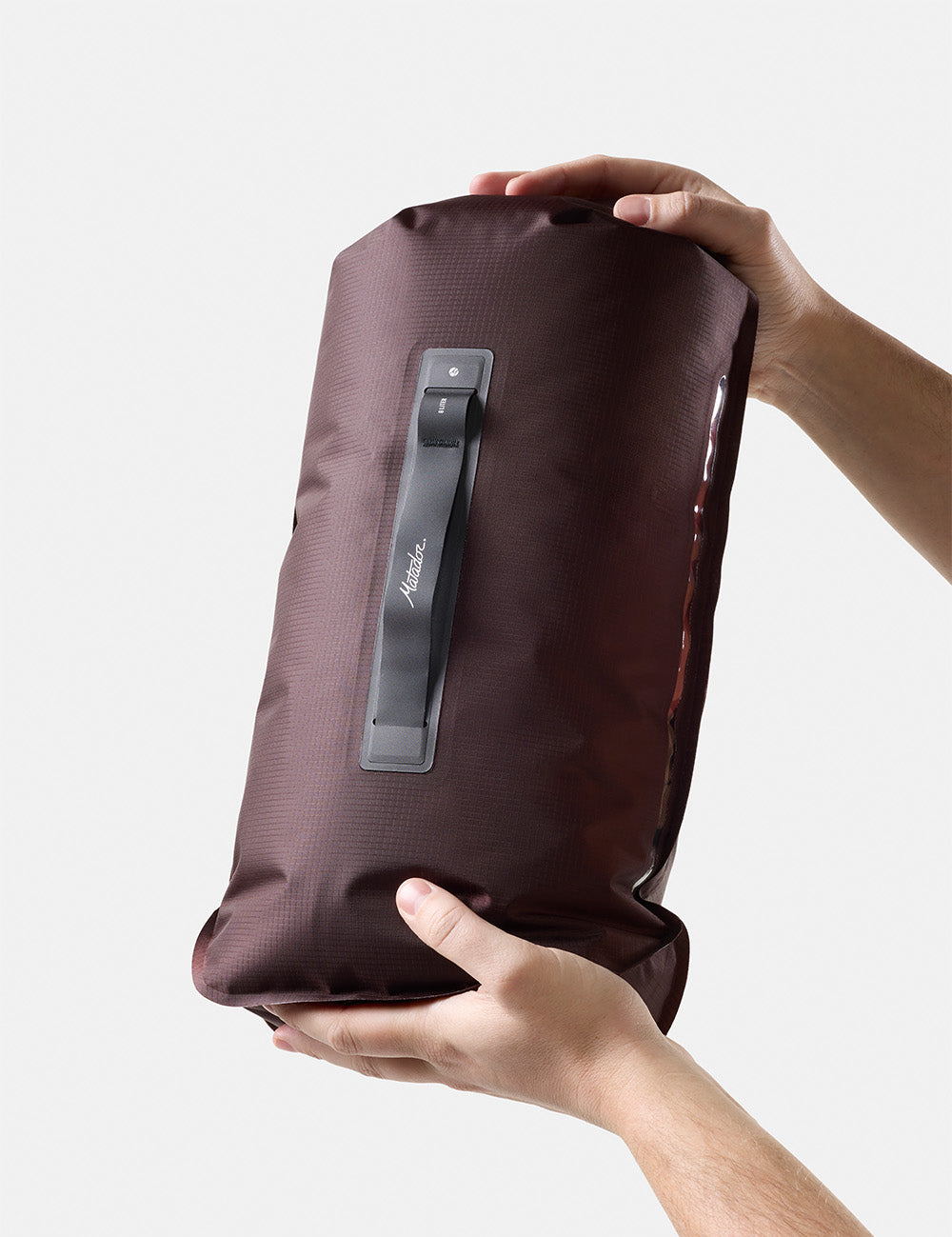 garnet dry bag with a handle held by hands on a light gray background