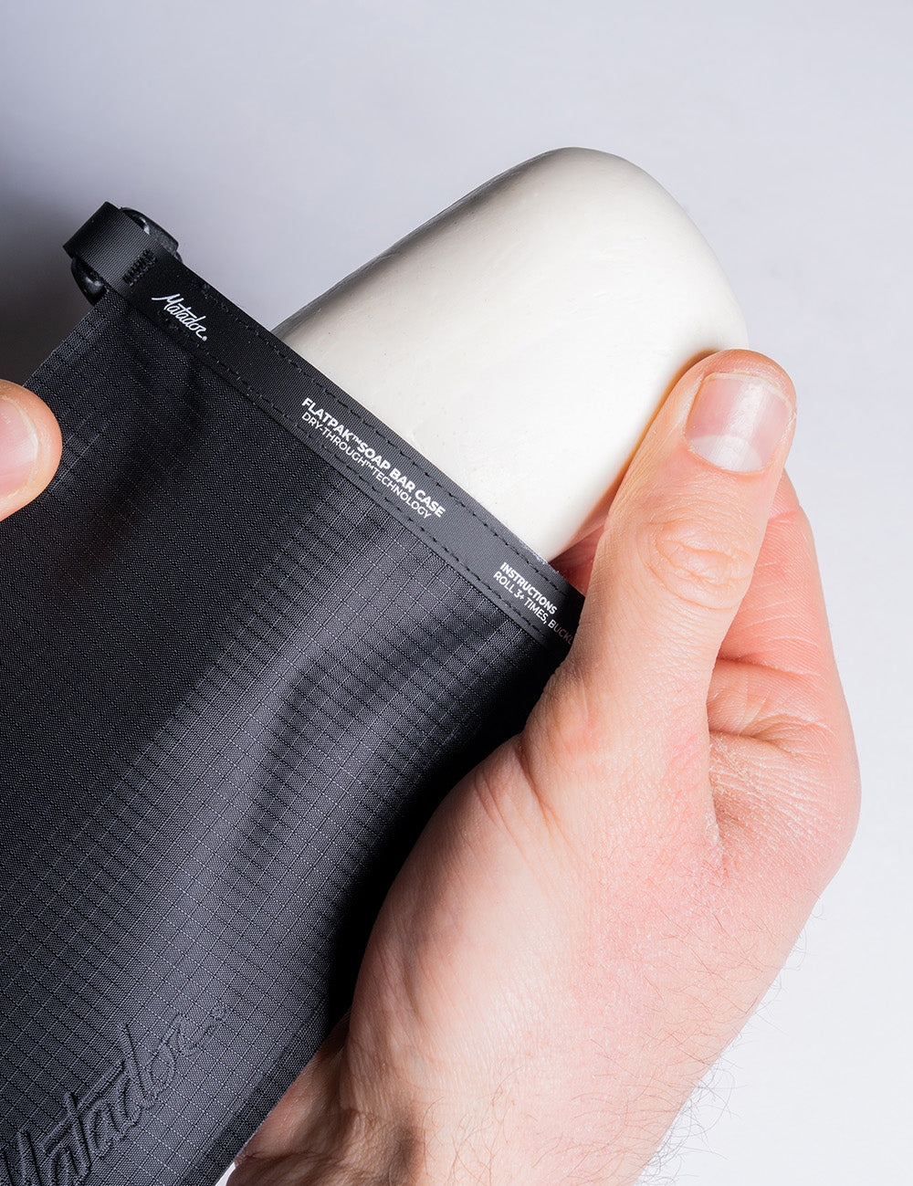 hand pulling white soap bar out of black soap bar case