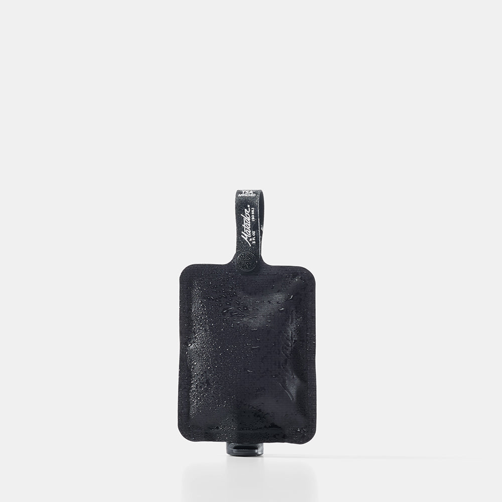 Black toiletry bottle with a strap on a white background