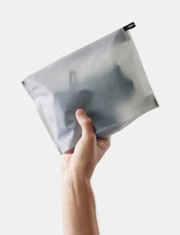 Hand holding white toiletry case on a white background