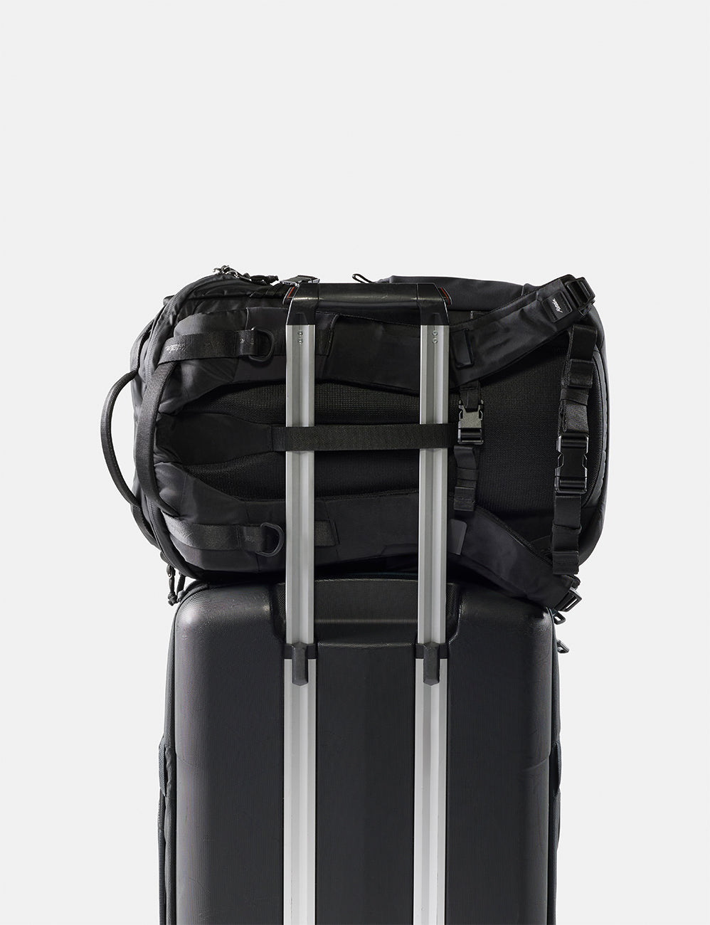Black backpack attached to a black suitcase on a white background