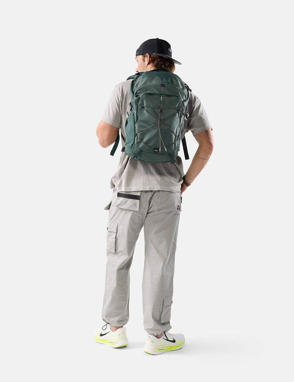 person wearing green backpack on white background