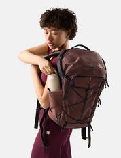 person pulling a water bottle out of garnet backpack