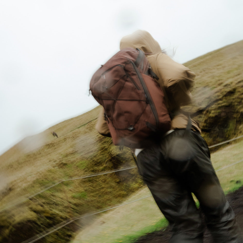 person in blurry rainy scene, wearing garnet backpack