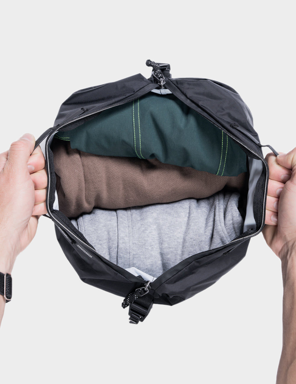 hands holding open gear cube with clothing inside