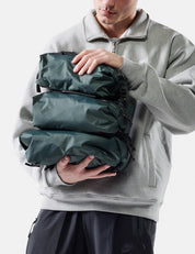 Person holding a green compression bag against a white background