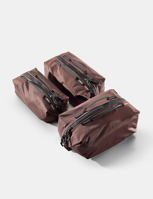 Three garnet gear cubes with zippers on a light gray background