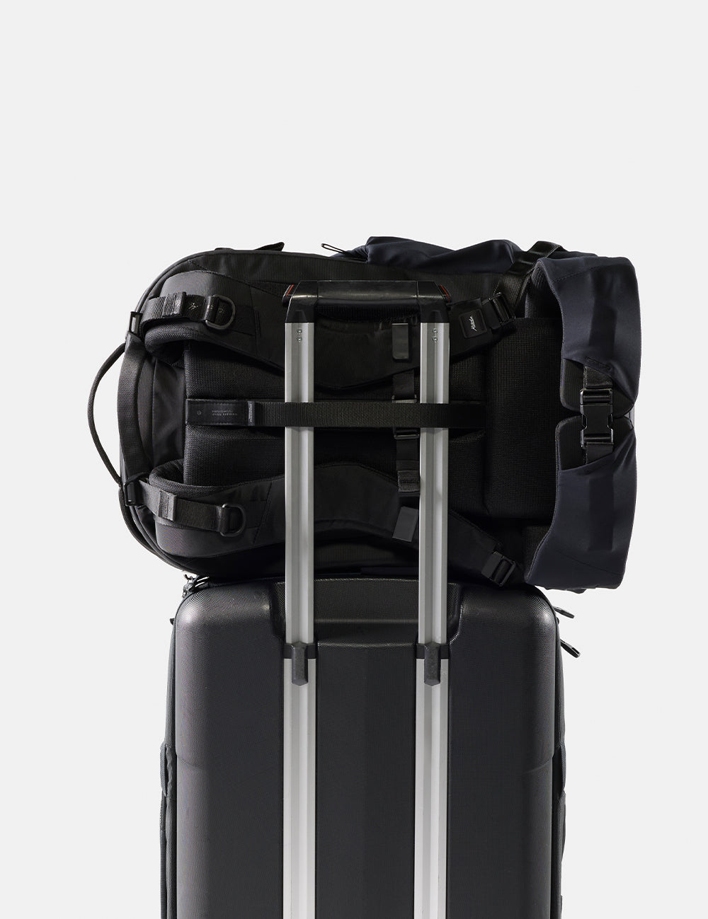 Black backpack on top of a black suitcase with a white background