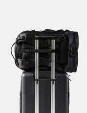 Black backpack on top of a black suitcase with a white background