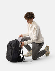 Man sitting on the floor with a black backpack and laptop on a white background