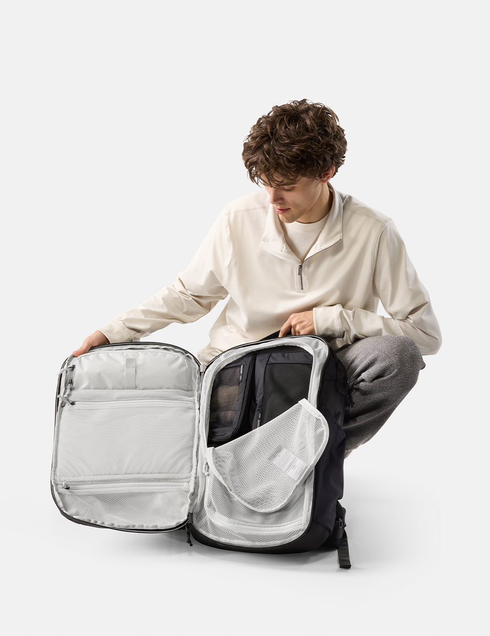 Person unpacking a large backpack on a white background