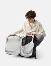 Person unpacking a large backpack on a white background