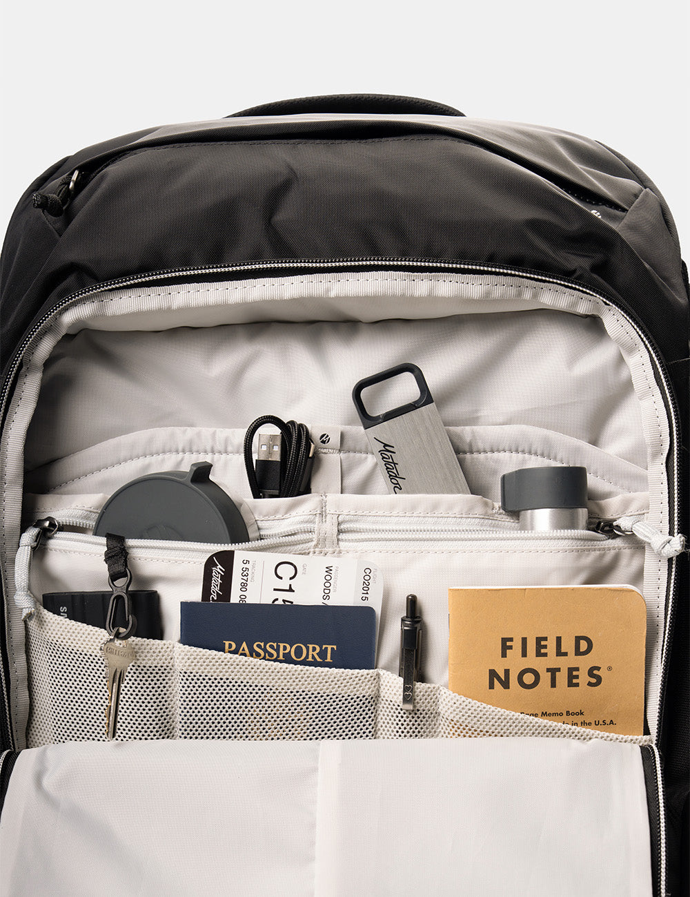 interior backpack pockets full of cords, keys, passport, pen, and notebooks