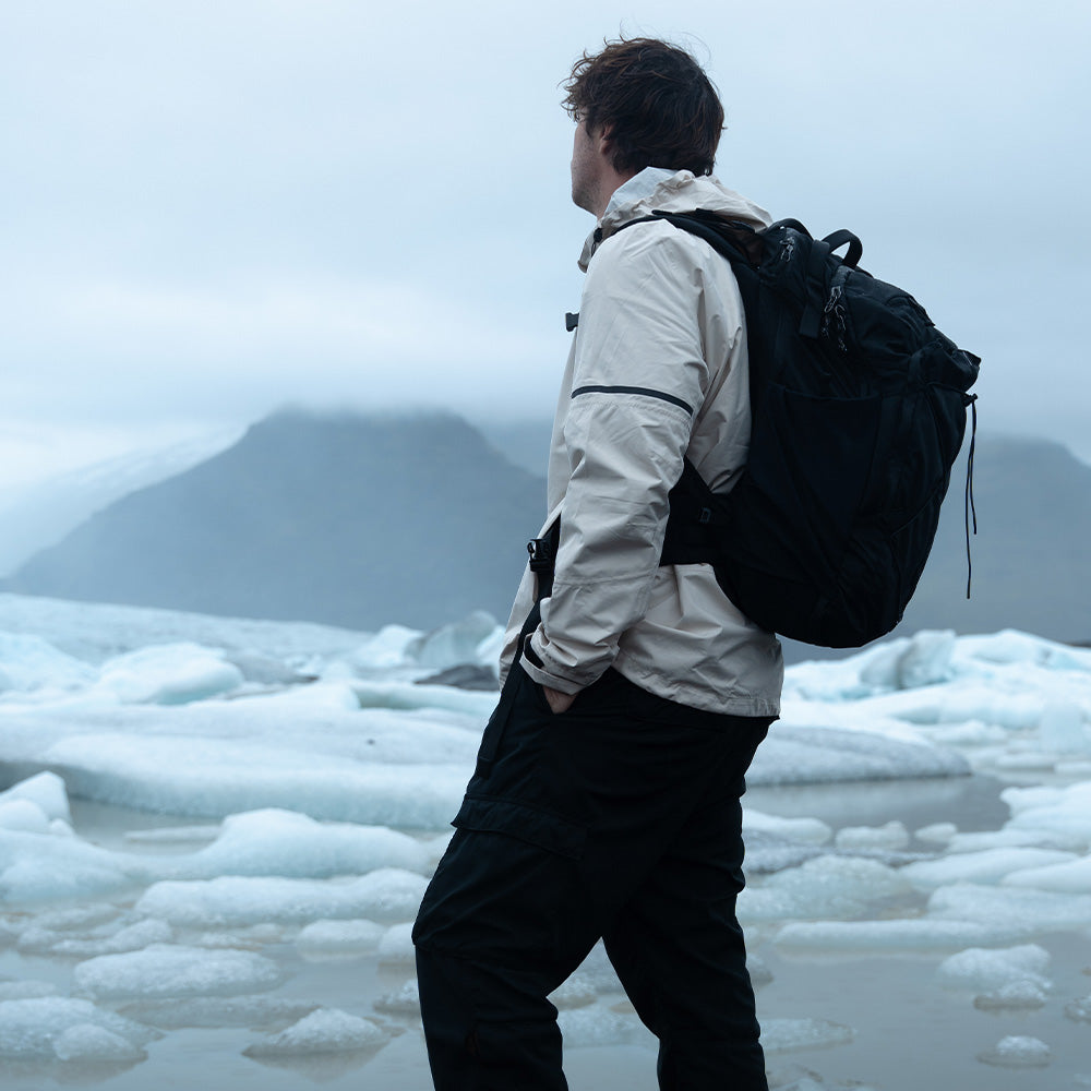 Person in front of icy ocean wearing black backpack