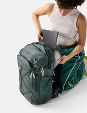 Person organizing items in a green backpack on a white background
