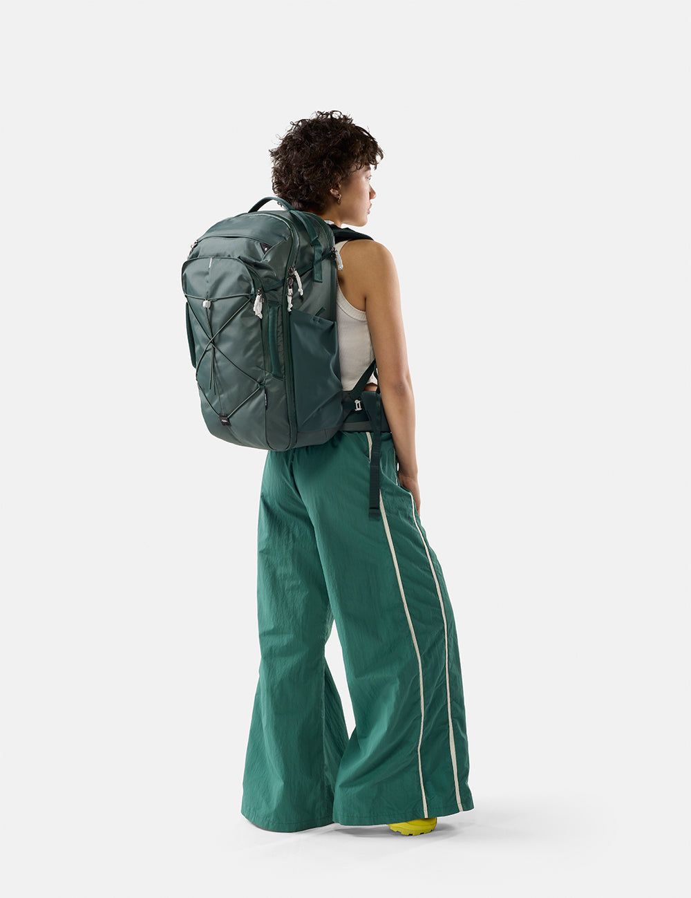Person wearing a green backpack and green pants on a white background