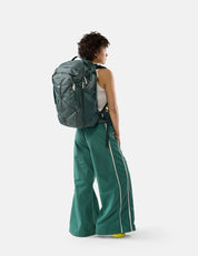 Person wearing a green backpack and green pants on a white background