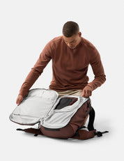 Man opening a garnet backpack with a clear compartment on a white background