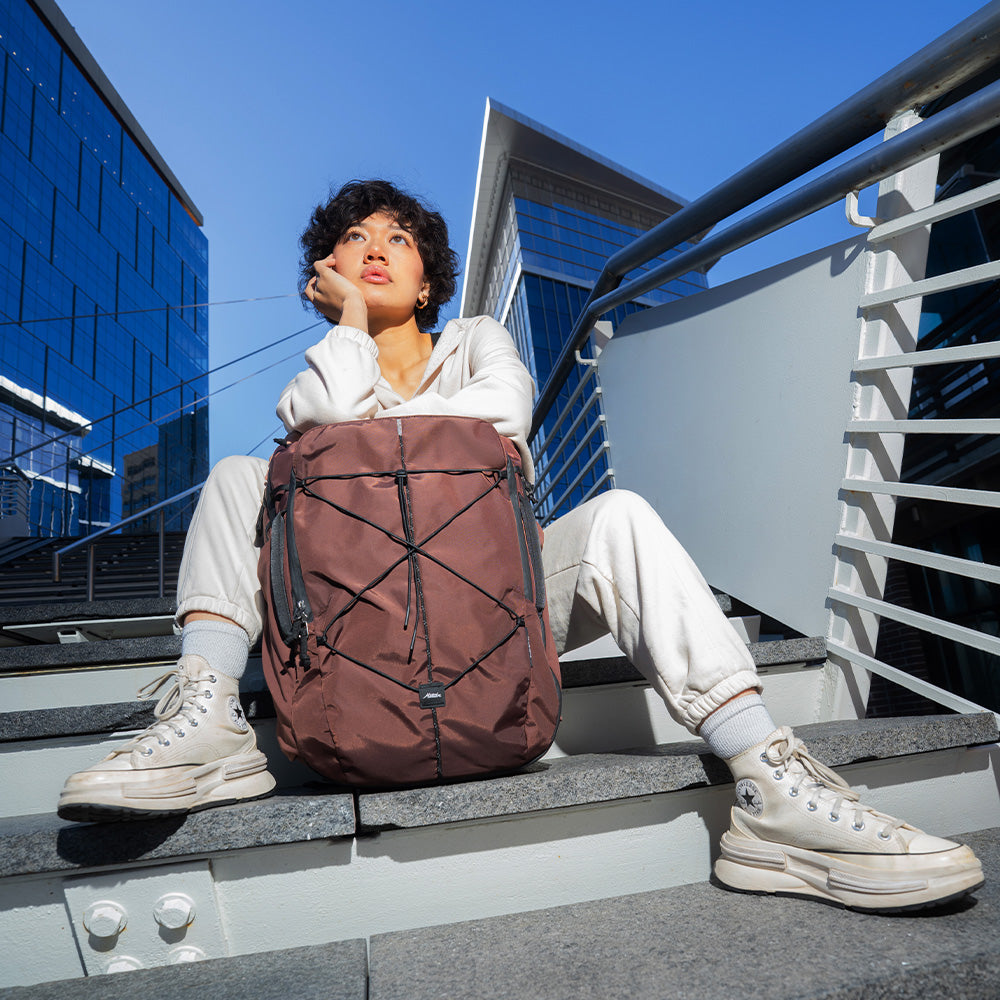 person sitting on concrete stairs with garnet bag