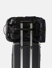 Black backpack on top of a suitcase with a white background