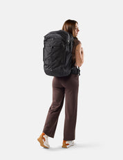 Person wearing a large black backpack on a white background