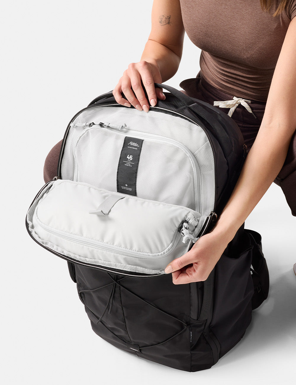 person opening top of black backpack