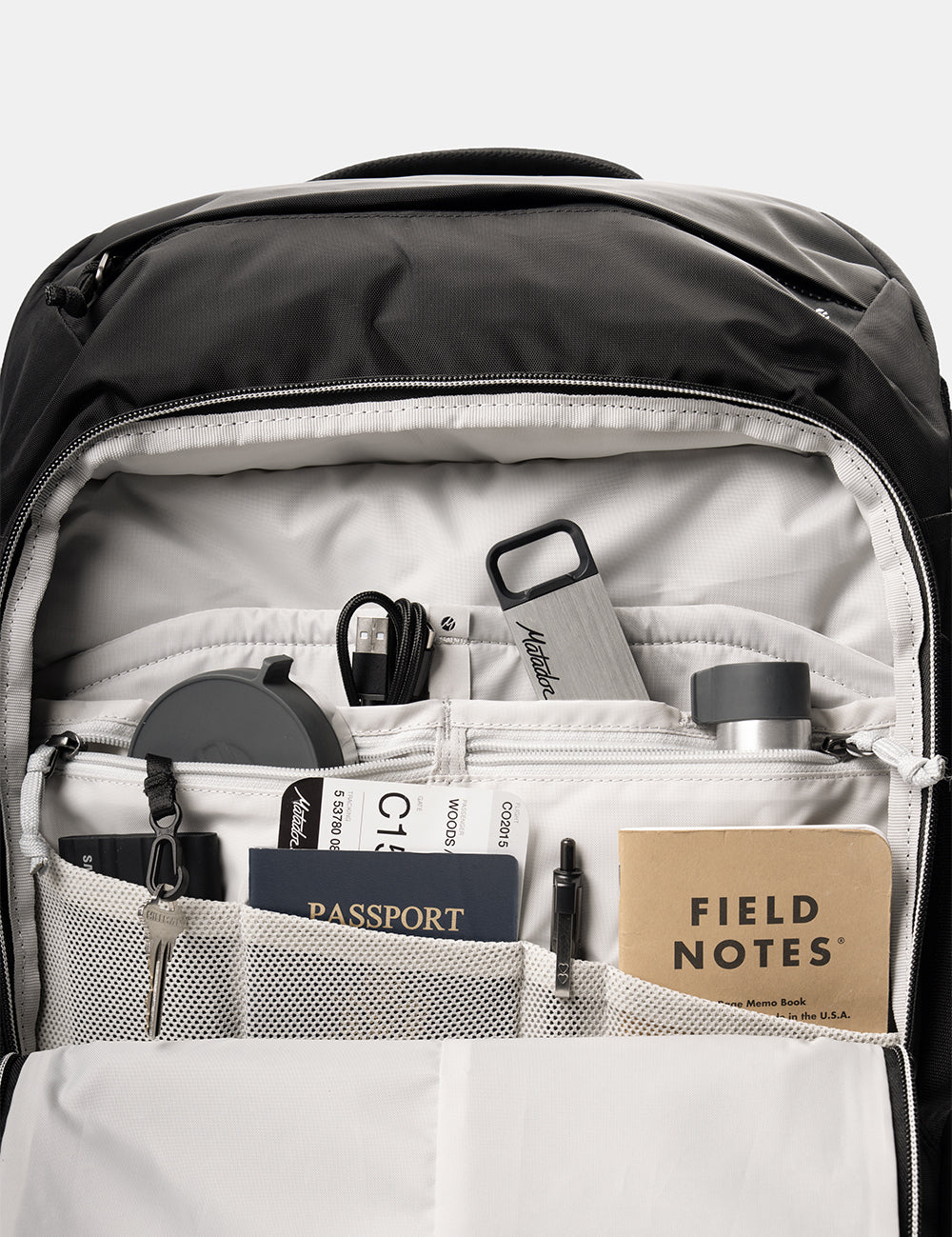 interior backpack pockets with passport, notebooks, cords, keys, and pill canisters